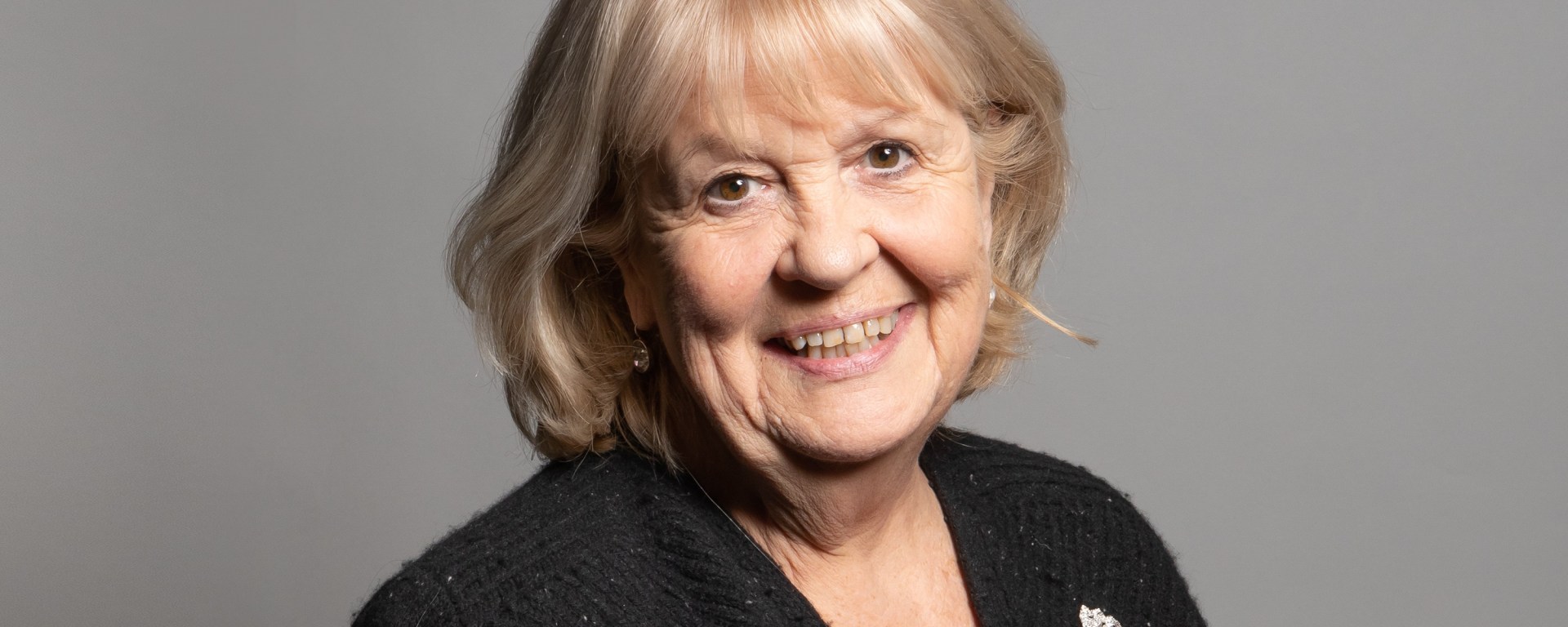 Headshot of a woman smiling, wearing a black top with brooch